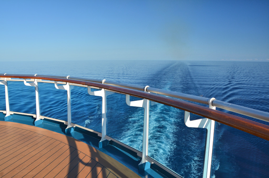 Blick über die Reling eines Kreuzfahrtschiffs auf das offene Meer. Die Kielspur des Schiffs zieht sich in die weite, blaue Ferne. Blick über die Reling eines Kreuzfahrtschiffs auf das offene Meer. Die Kielspur des Schiffs zieht sich in die weite, blaue Ferne.