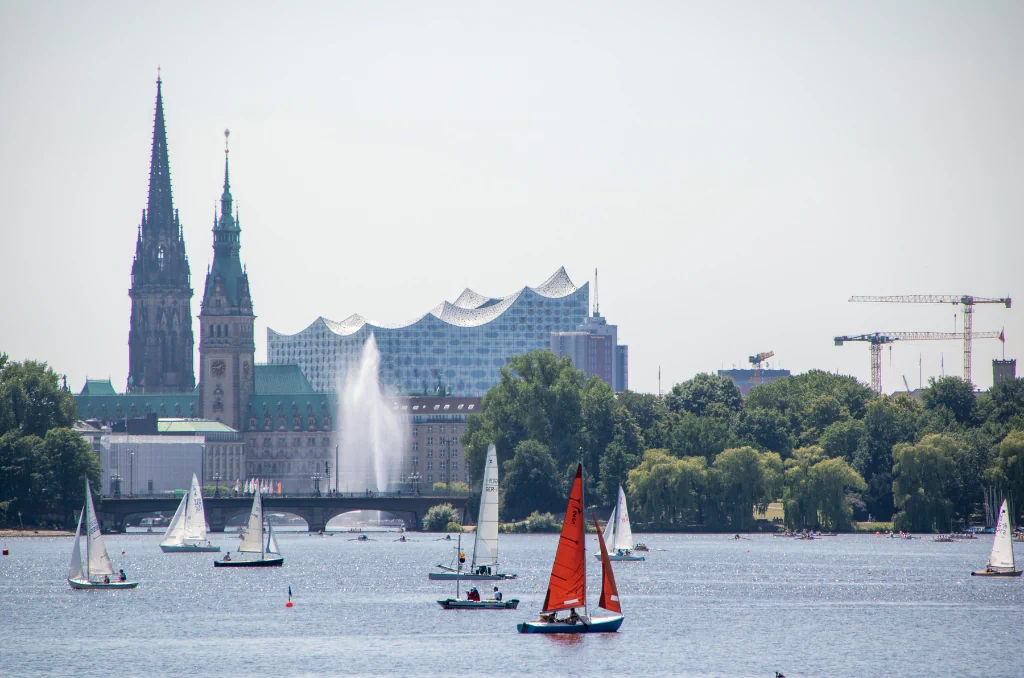Ein sonniger Tag auf der Hamburger Außenalster mit Segelbooten und der berühmten Skyline im Hintergrund, inklusive Elbphilharmonie und Rathaus. Ein sonniger Tag auf der Hamburger Außenalster mit Segelbooten und der berühmten Skyline im Hintergrund, inklusive Elbphilharmonie und Rathaus.